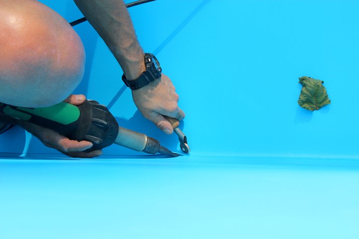 A worker welds plastic cover for water pool. Water pool cover replacement.