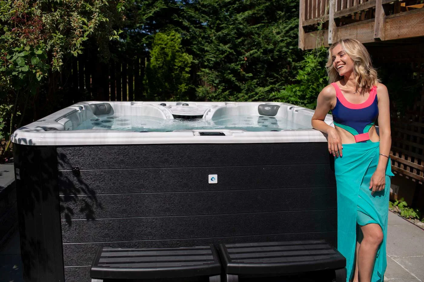 woman standing and smiling next to clearwater spa in backyard